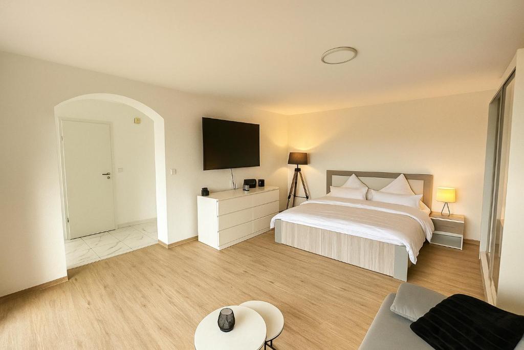 a bedroom with a bed and a flat screen tv at Modernes Apartment mit 180° Bergblick in Buchenberg