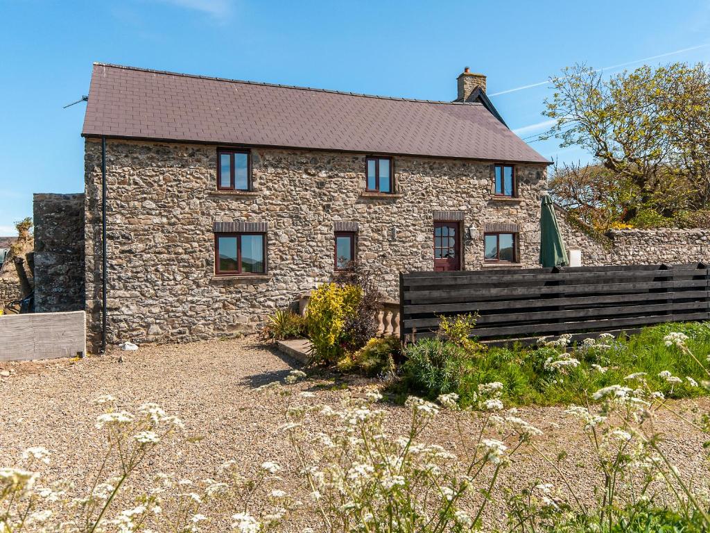 ein Steinhaus mit einer Bank davor in der Unterkunft Carn Llidi Cottage in St. Davids