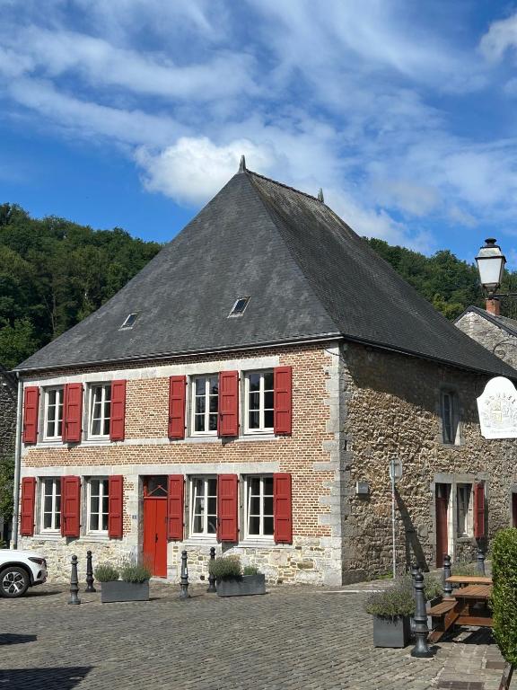a large brick building with red shutters on it at Maison de la Fontaine in Hierges