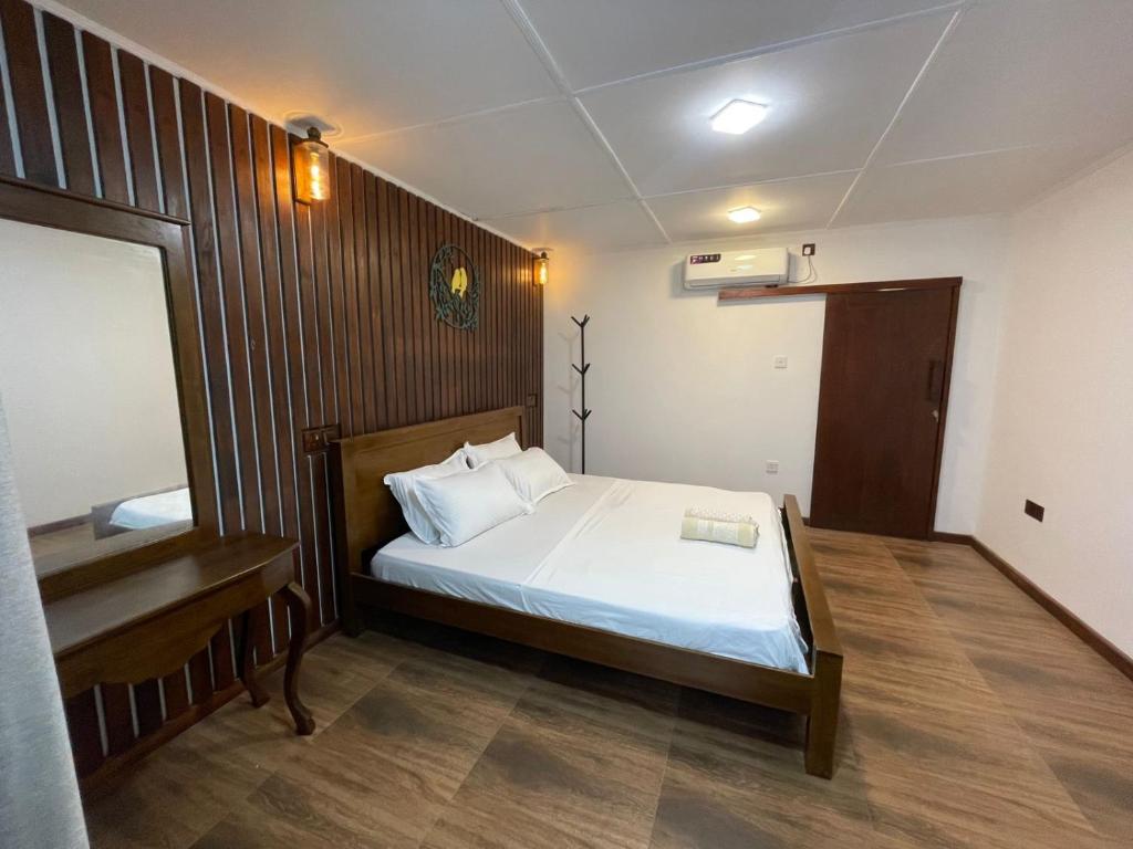 Un dormitorio con una cama y una pared de madera. en Aethera Stay, en Mirissa