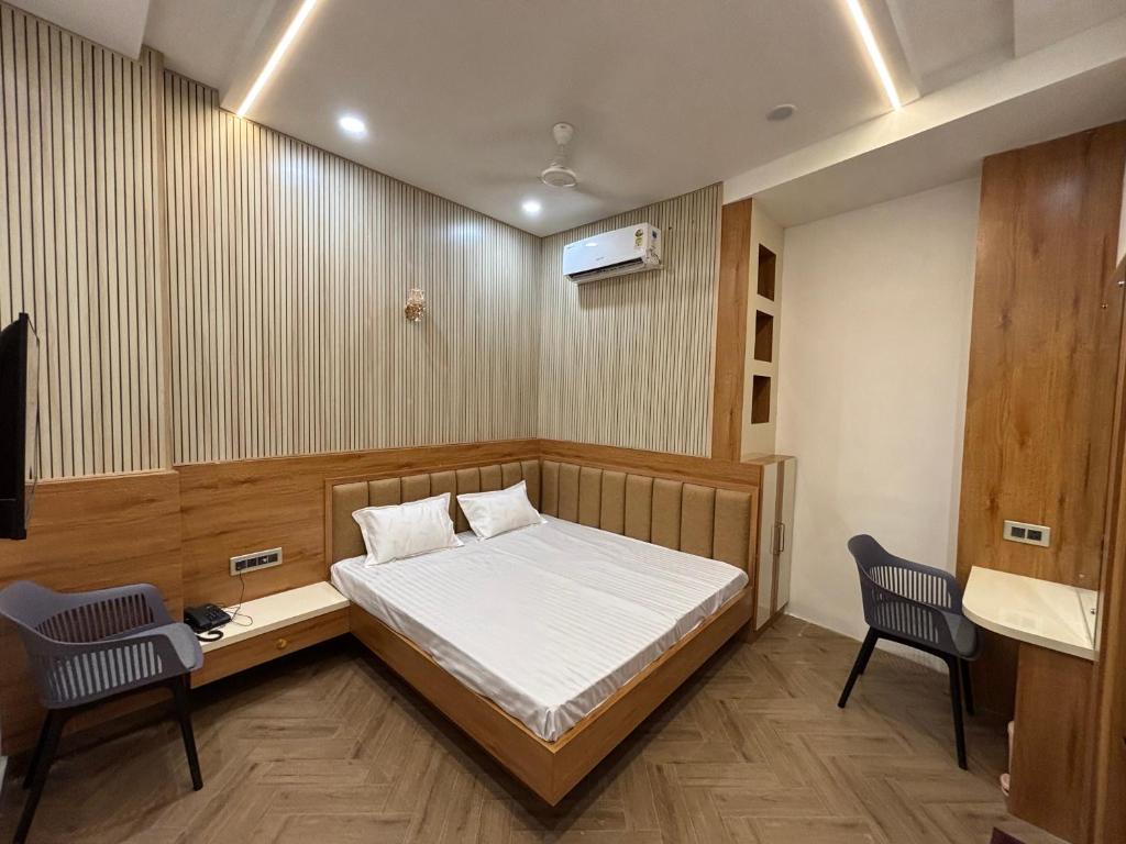 a bedroom with a bed and a desk and two chairs at Comfort Inn in Sahāranpur