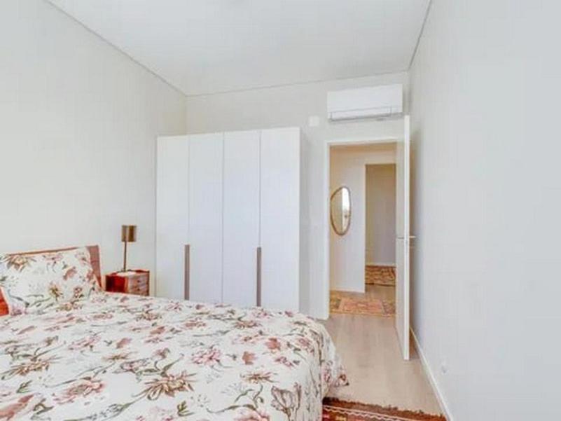 a white bedroom with a bed and a staircase at Super apartamentos para qualquer um de Silva in Paço de Arcos