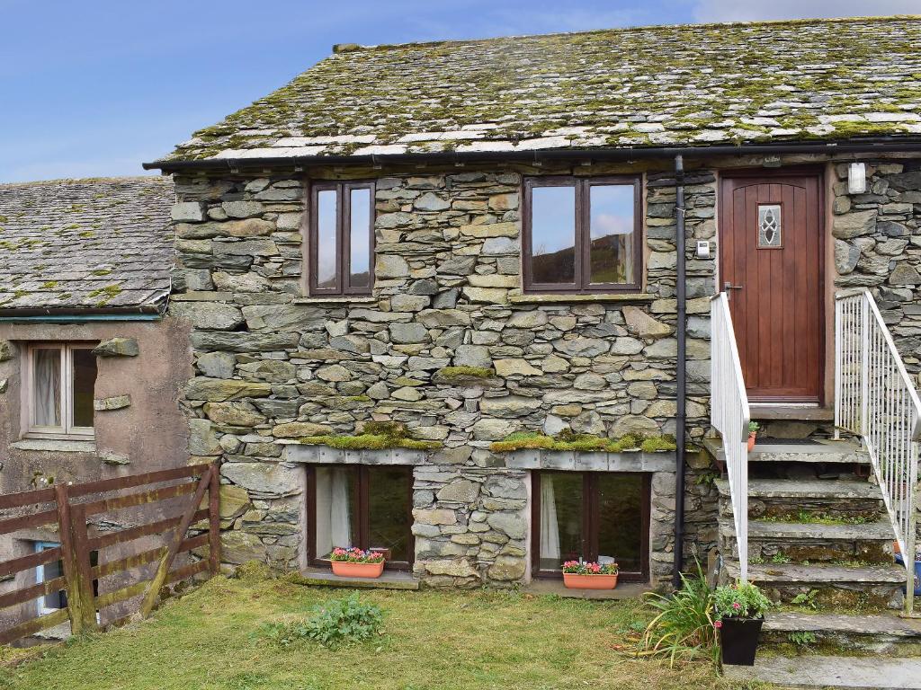 an old stone house with a wooden door and stairs at Willow Cottage in Ambleside