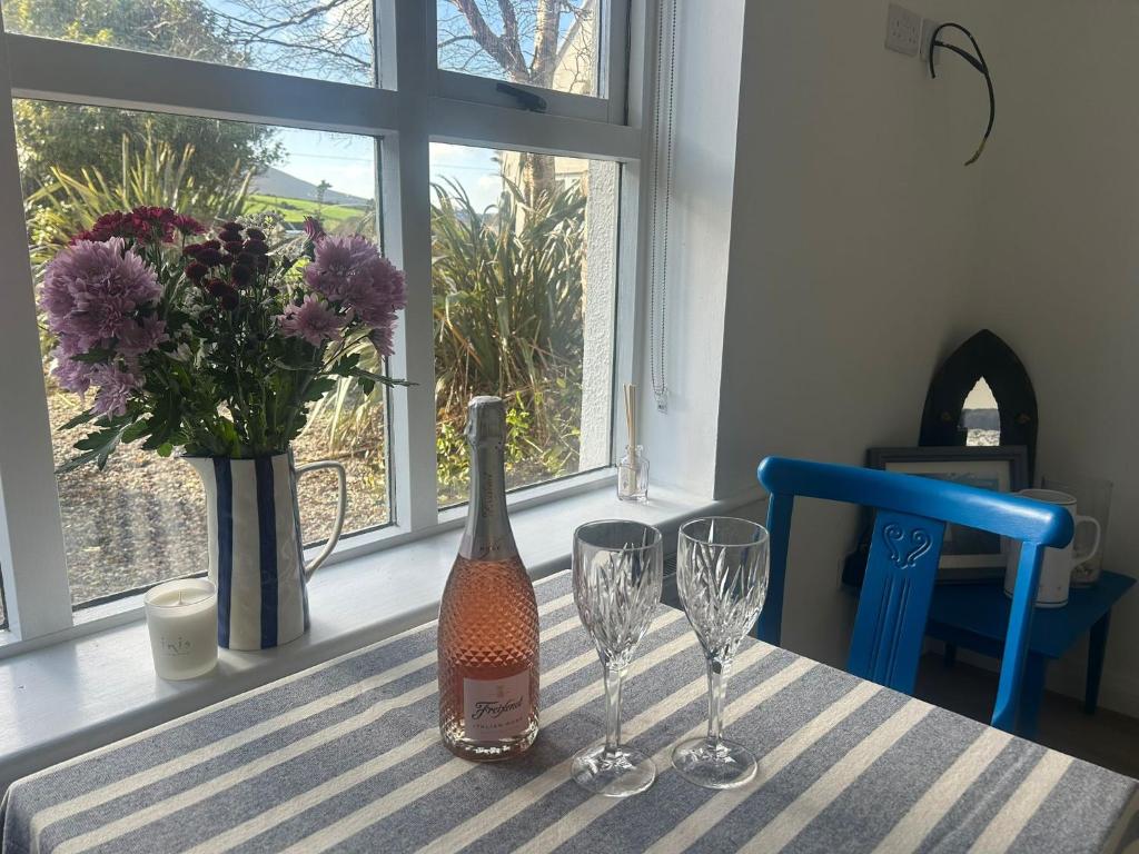 ein Tisch mit einer Flasche Wein und zwei Weingläsern in der Unterkunft Westport Coastal Cottage in Westport