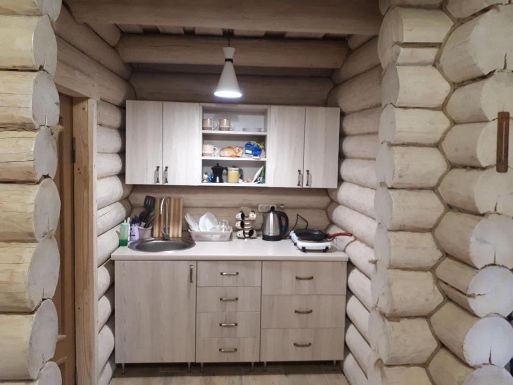 - une cuisine avec des placards blancs et un mur en pierre dans l'établissement Садиба Bokoras, à Vyshka