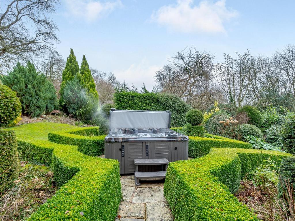 an outdoor grill in a garden with hedges at Old Upper Gwestydd in Highgate