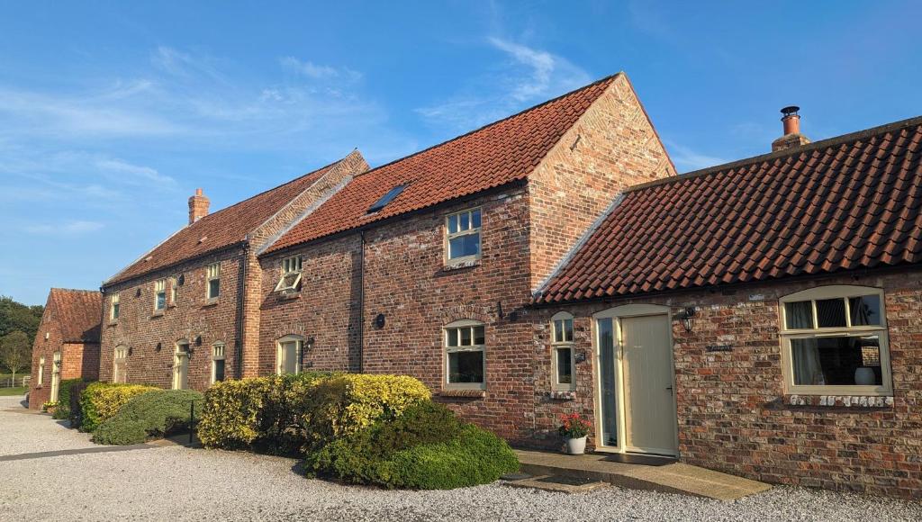 ベバリーにあるHigh Barn 6 bedroomsの前に茂みがあるレンガ造りの建物の列