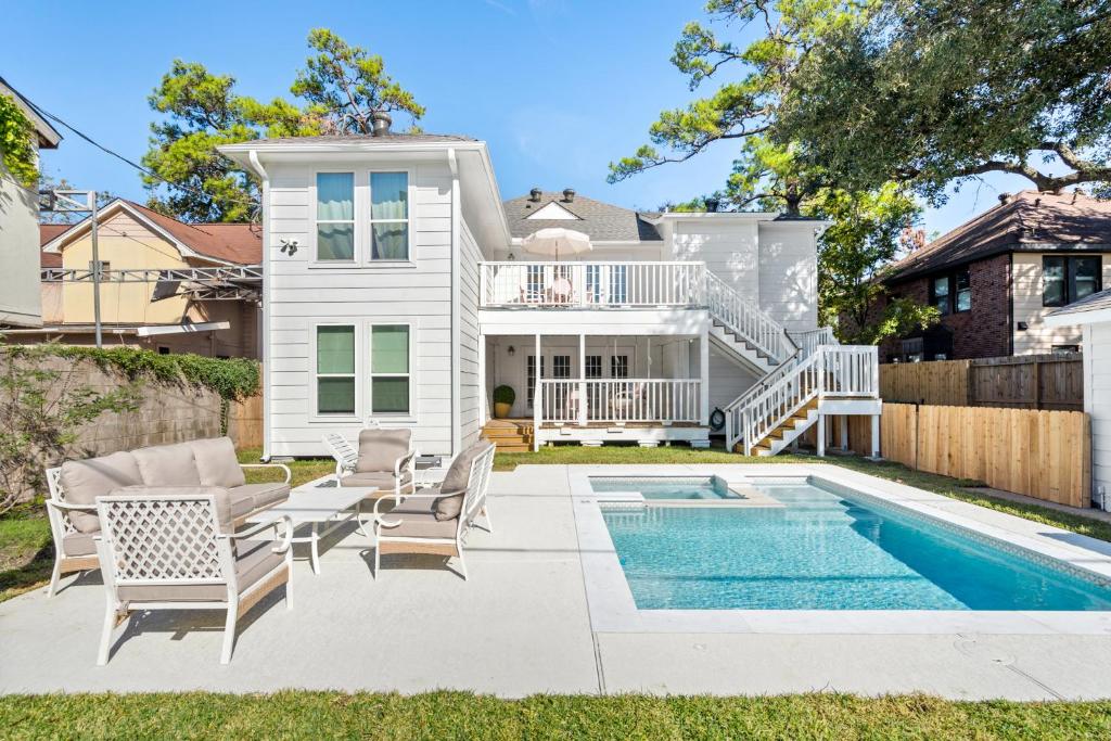 a home with a swimming pool and patio furniture at Downtown 10 min, 90 degree F Pool & Spa, Linked 2 homes, Gated Parking in Houston