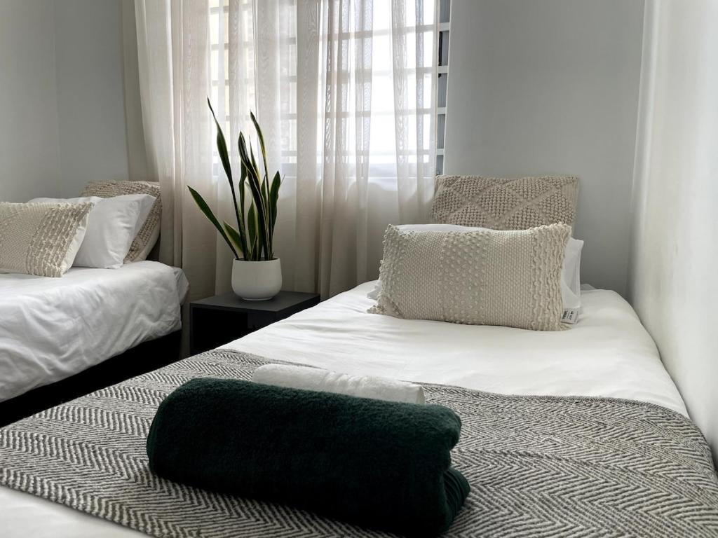 a room with two beds with pillows and a window at Surf & Stay - Muizenberg Beach in Muizenberg