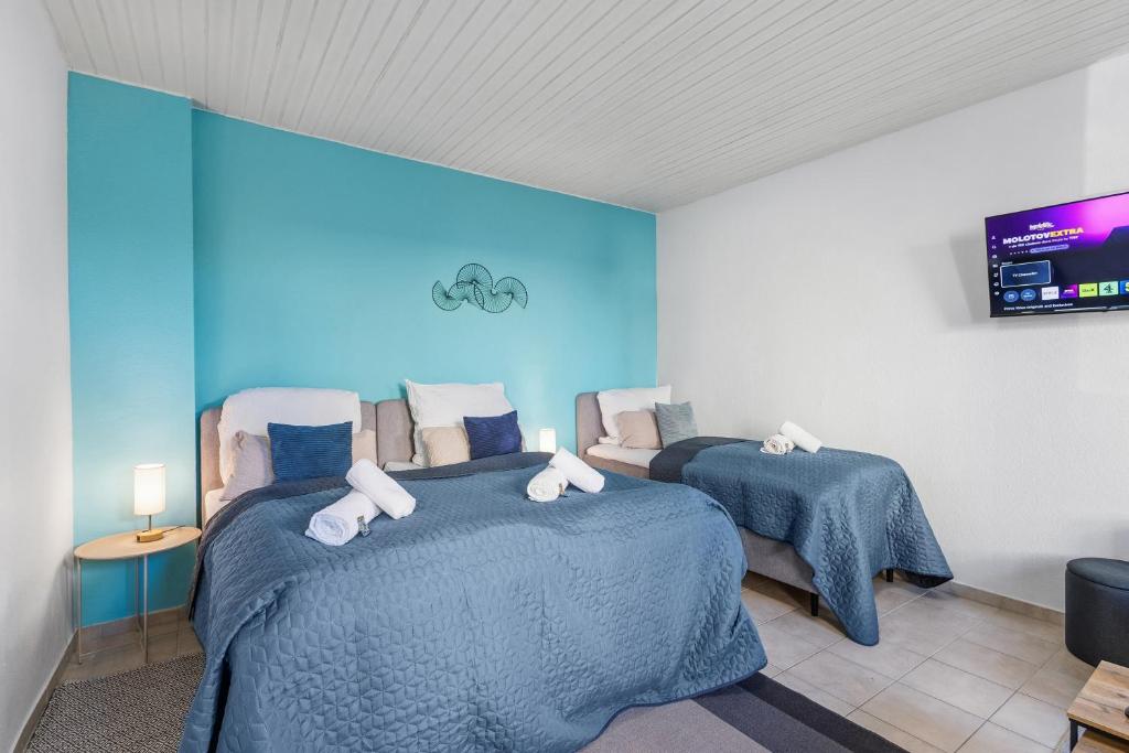 two beds in a room with blue walls at Goltan Apartment - Küche - WLAN - Parkplatz in Straubing