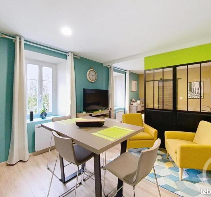 una sala de estar con una mesa y sillas en Cosy F2 proche parc thermal VITTEL, en Vittel