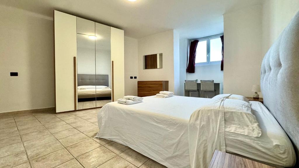 a bedroom with a white bed and a mirror at Fronte Mare Ampio Quadrilocale in Alassio