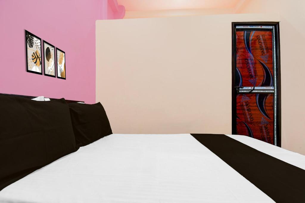 a bedroom with a white bed and a red door at Hotel O Welcome Guest House in Patna