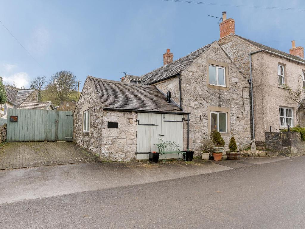 an old stone house with a garage on a street at The Smithy - E5445 in Brassington