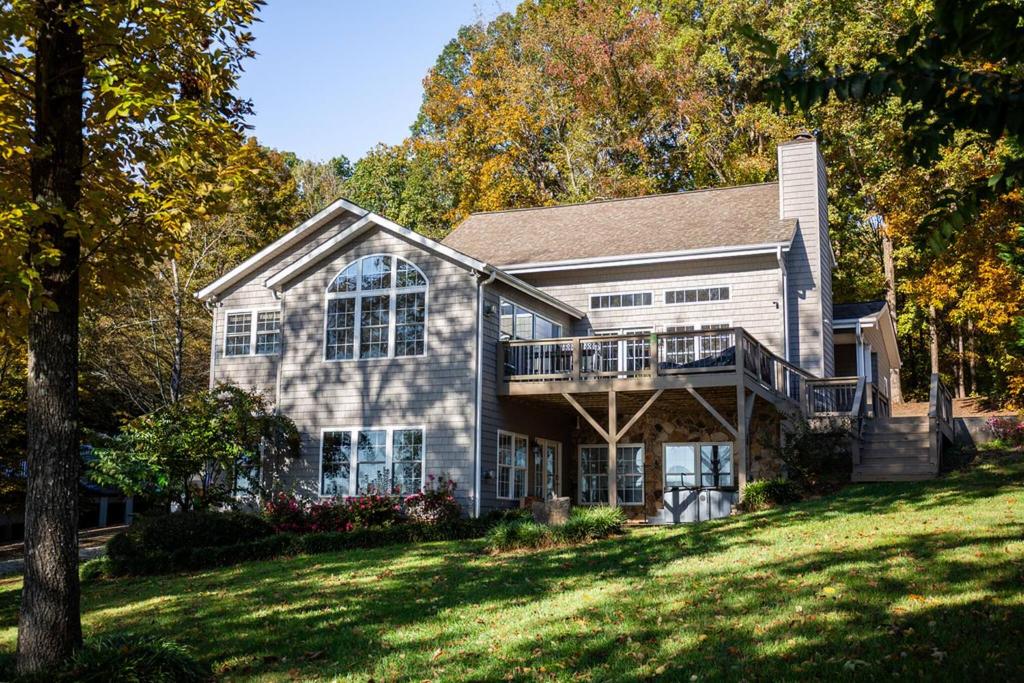 a house with a porch and a deck on a lawn at Dockside Dream – Your Perfect Waterfront Escape in Lexington