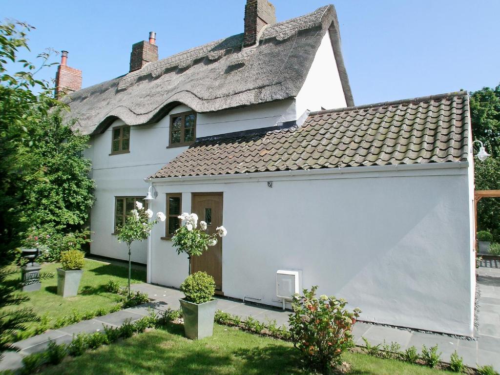 a white cottage with a thatched roof at May Cottage in Bacton