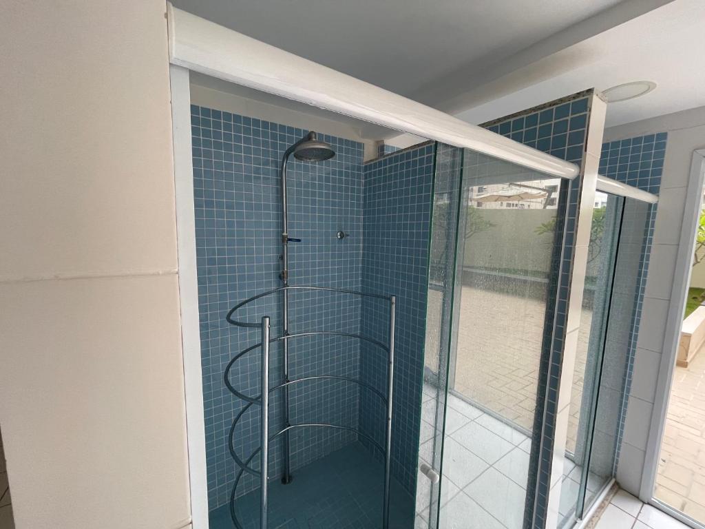 La salle de bains est pourvue d'une douche et de carrelage bleu. dans l'établissement Lindo apartamento 124C com vista mar e lazer de clube, à Guarujá