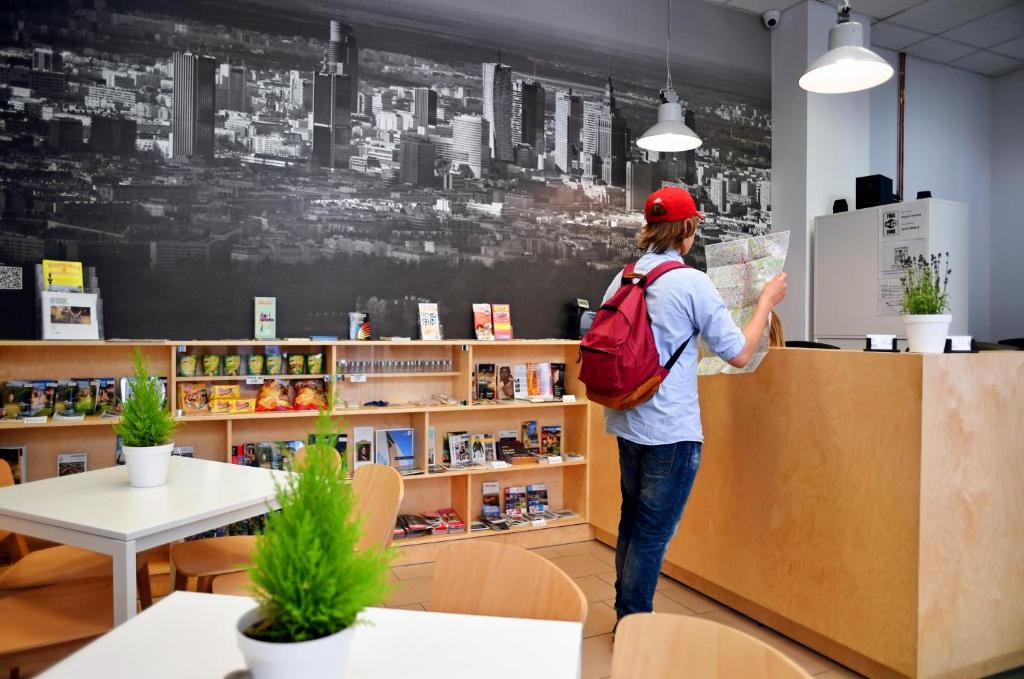 a man standing in front of a book shelf at Warsaw Hostel Centrum in Warsaw