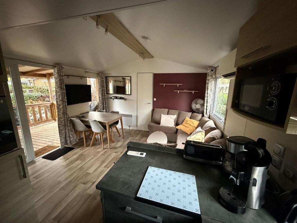 a living room with a couch and a table at Mobil-home 565 tout confort camping SIBLU 4 étoiles in Gastes
