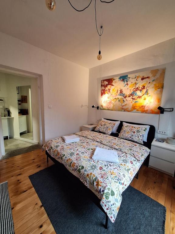 a bedroom with a bed and a painting on the wall at Cozy City Centar Studio in Podgorica