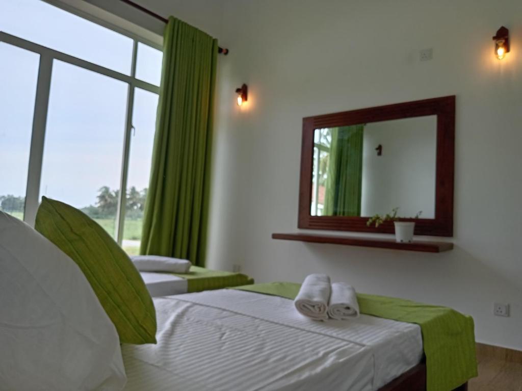 une chambre avec deux lits et un miroir dans l'établissement Paddi Breeze Cottage - Yala Safari, à Lukasgoda