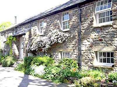 an old stone building with windows and plants in front of it at 2 Farfield Cottages in Sedbergh