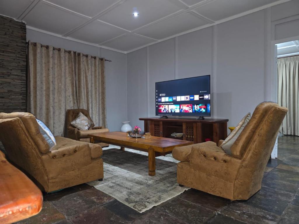 a living room with two chairs and a television at Nandoni Maritime Home in Thohoyandou