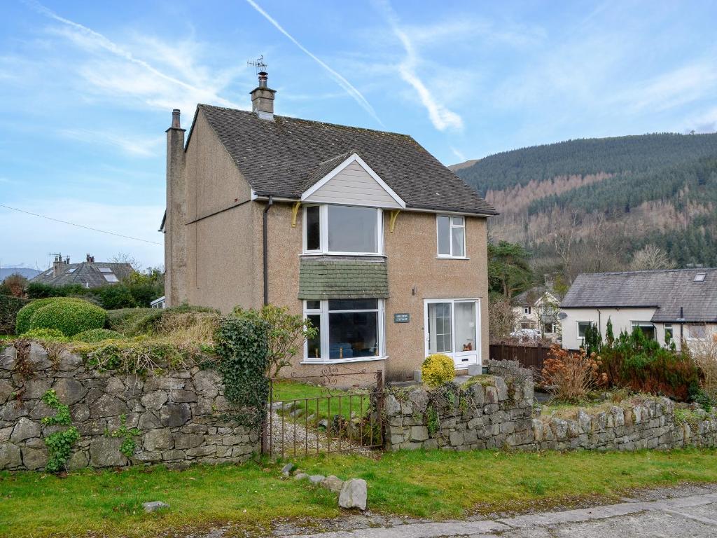 a brick house with a stone wall at Hillside Cottage in Keswick