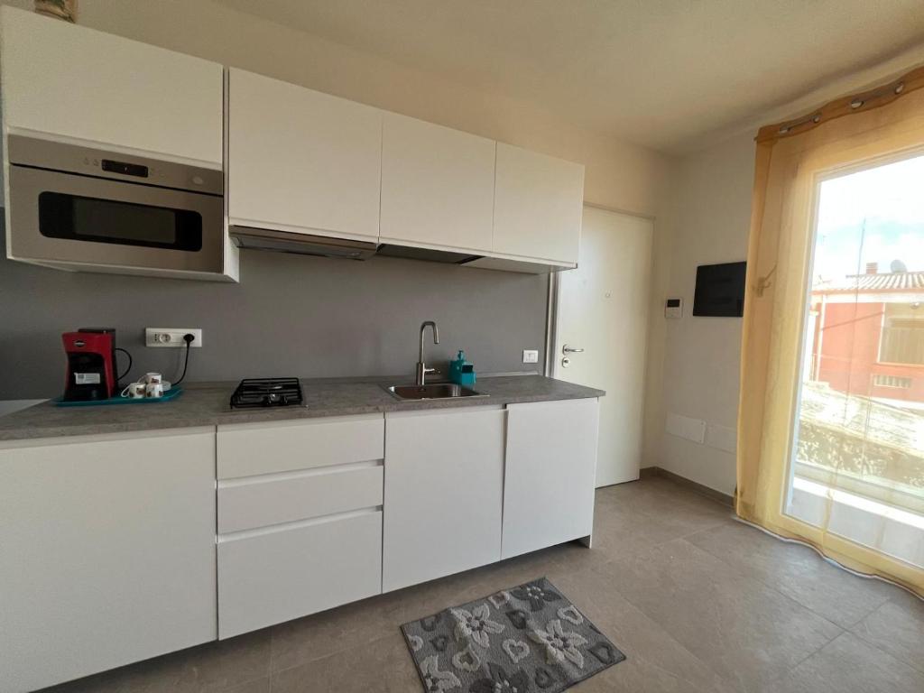 a kitchen with white cabinets and a sink and a window at Casa Via Marconi in Assemini