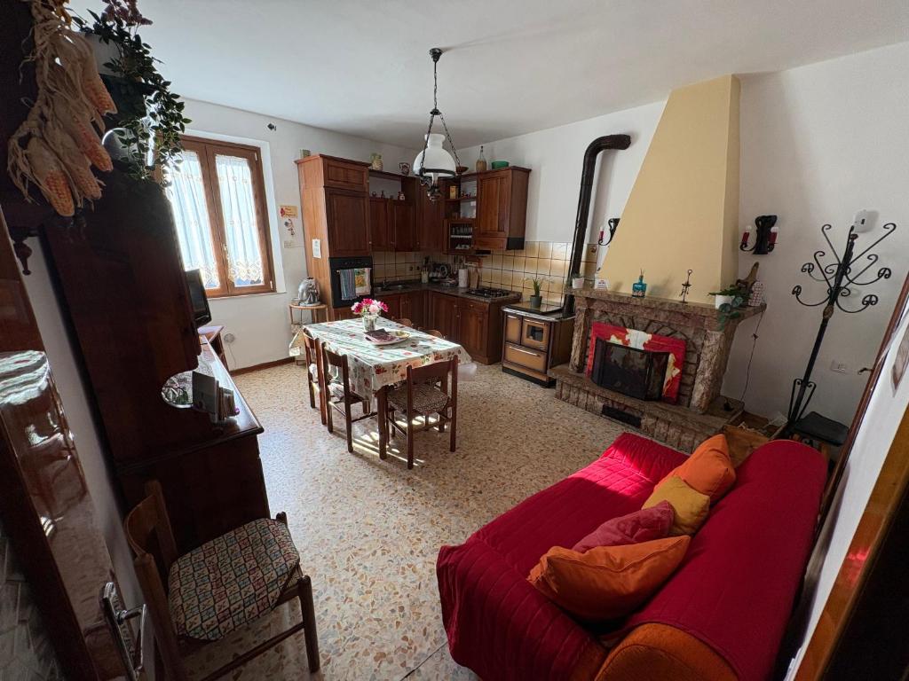 un salon avec un canapé rouge et une cuisine dans l'établissement La casa di Nonna nel Piazzalino Asciano Siena Crete Senesi, à Asciano