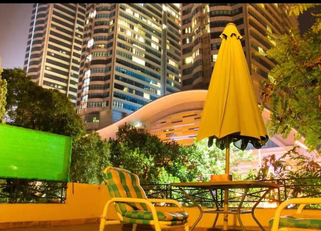 a table with a yellow umbrella and chairs in a city at Livin Hub Guest House in Islamabad