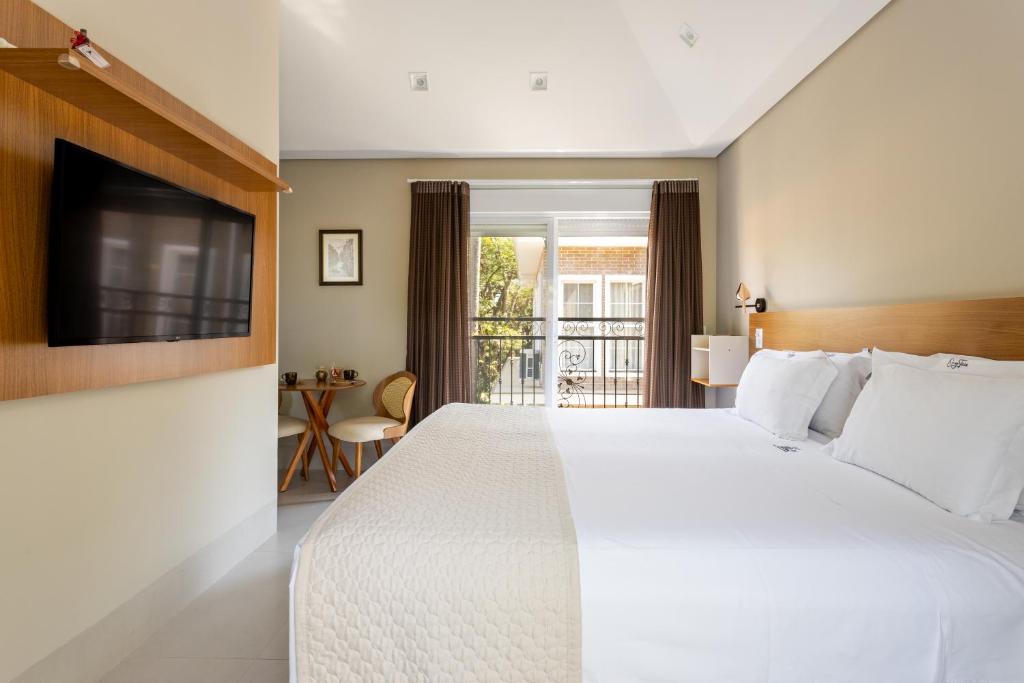 a hotel room with a bed and a television at Vilinha típica - Suíte Onze Tuin - Entrada com senha - Somos hospedagem por temporada in Holambra