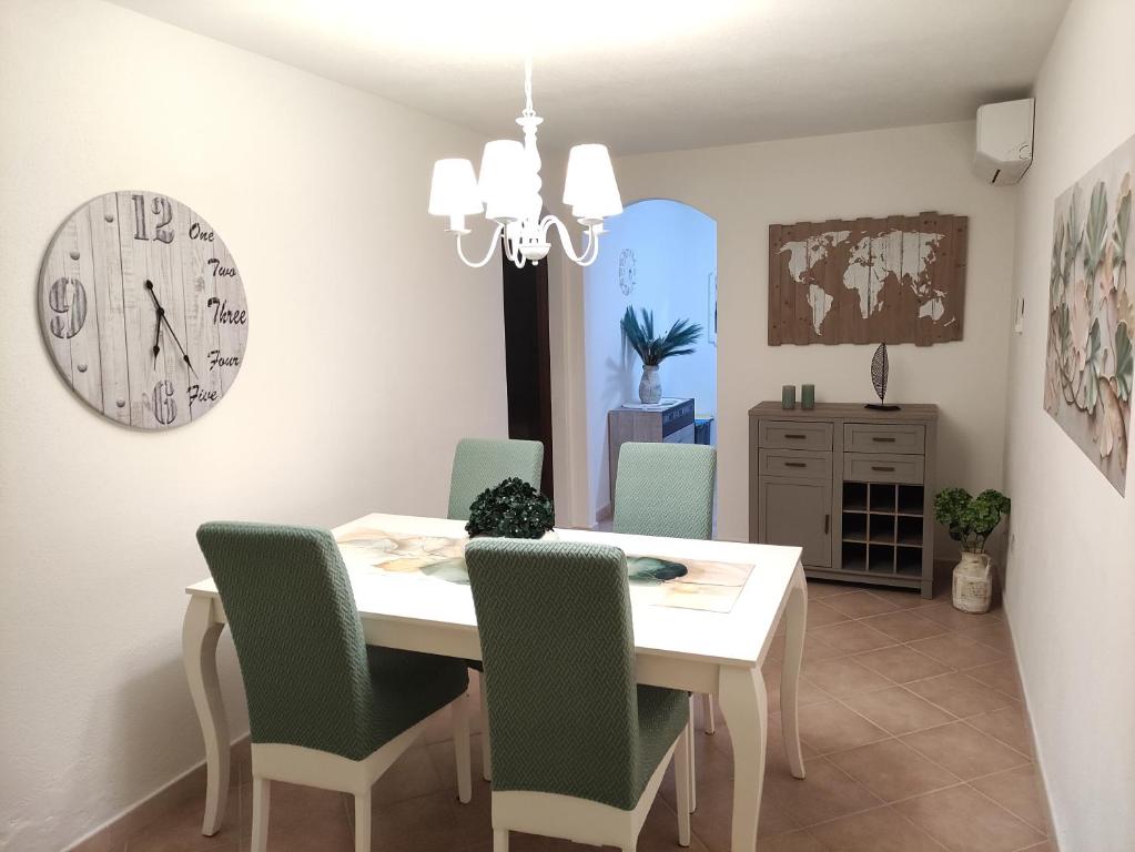 ein Esszimmer mit Tisch und Stühlen und einer Uhr in der Unterkunft Casa vacanza - Ambra's Homes in Trinità dʼAgultu