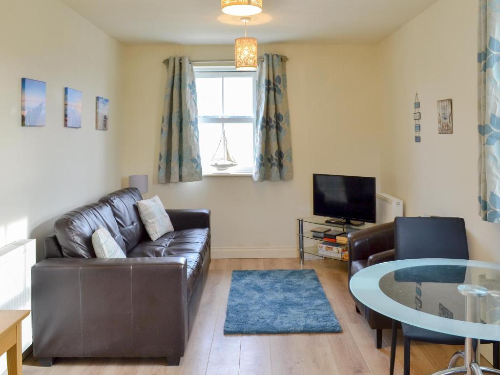 a living room with a leather couch and a table at The Parade Apartment in Reighton