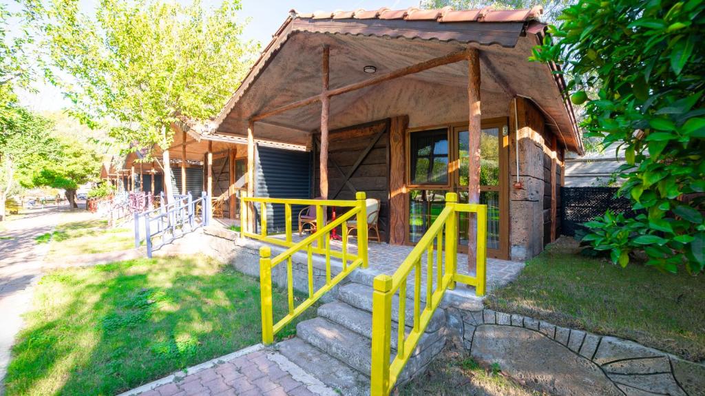 ein kleines Haus mit einem gelben Zaun davor in der Unterkunft Welt Bungalows Belenbaşı in Hurmaköy