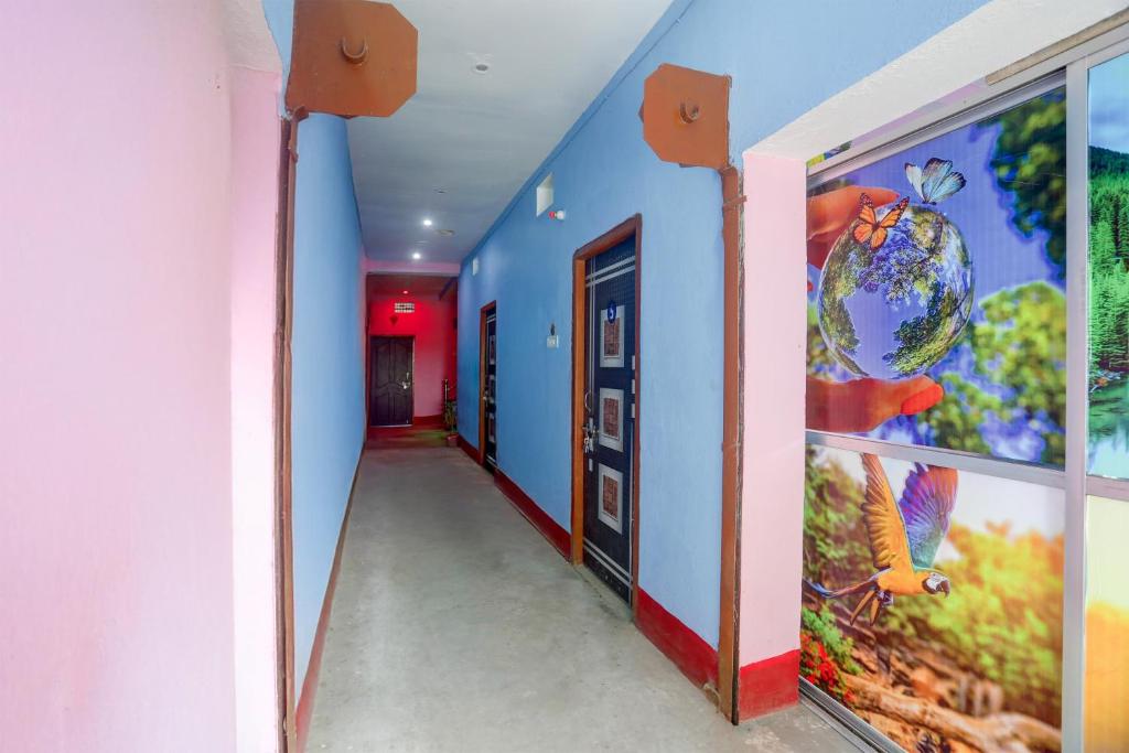 a hallway with blue walls and paintings on the walls at spot On Happy Awashi Hotel in Patna City