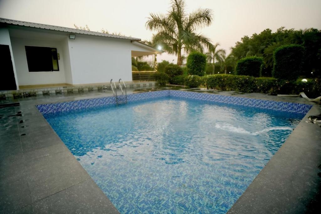 a swimming pool with blue water in front of a house at Blue Heaven Farm Villa in Noida