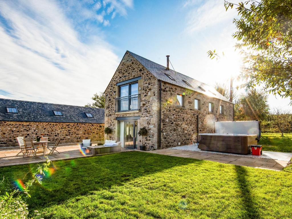 an exterior view of a stone house with a lawn at The Cart House in Duns