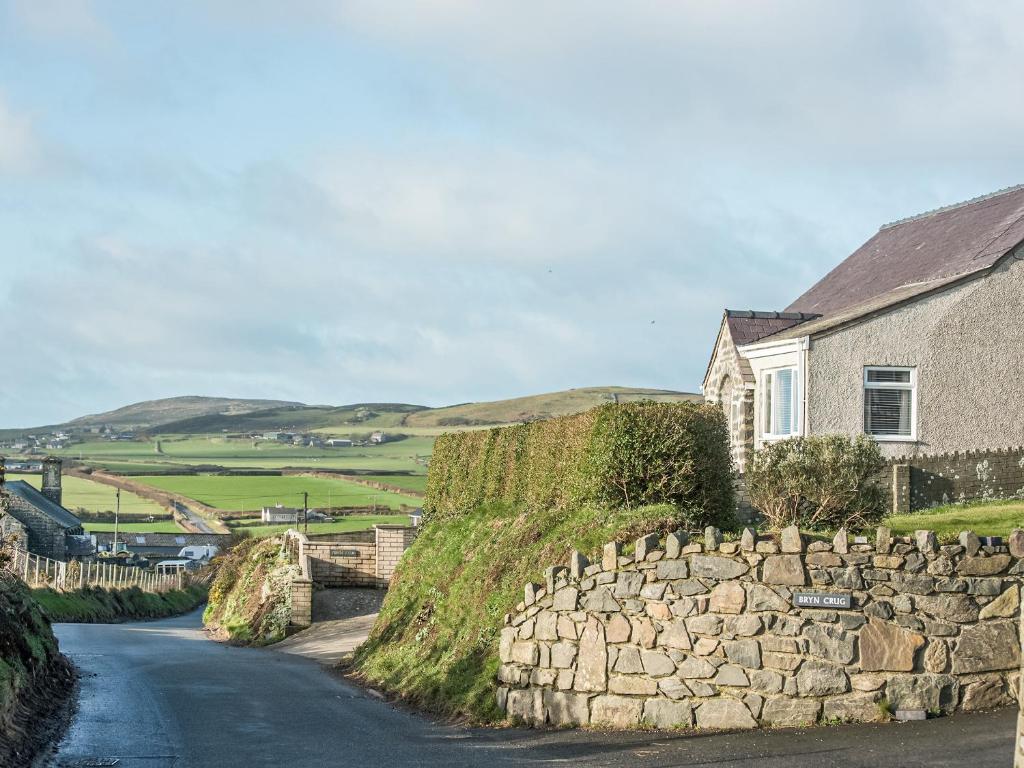 ein Haus und eine Steinmauer neben einer Straße in der Unterkunft Island View - Cottage in Aberdaron