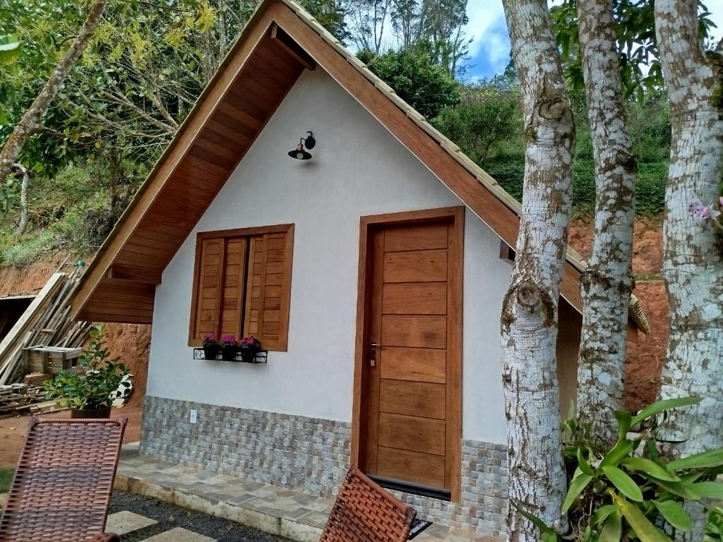 a small white house with a wooden door at Chalé Sognare Due in Santa Teresa
