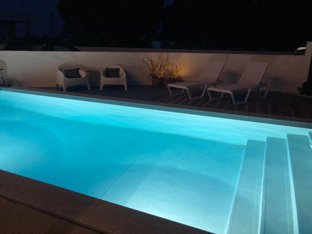 a swimming pool at night with chairs and tables at Ikigai B&B in Carvalhal