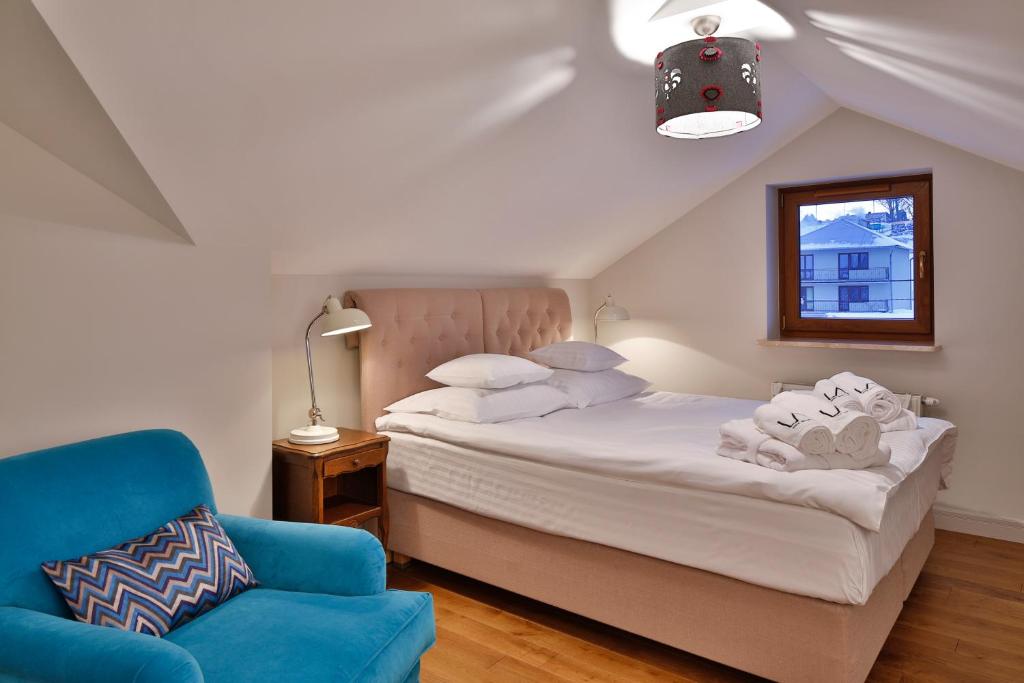 1 dormitorio con 1 cama y 1 silla azul en Lemon Apartments, en Krynica-Zdrój