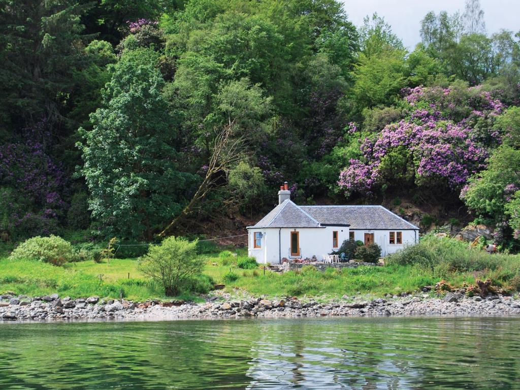 ein kleines weißes Haus am Ufer eines Flusses in der Unterkunft Shore Cottage - S4600 in Tarbert
