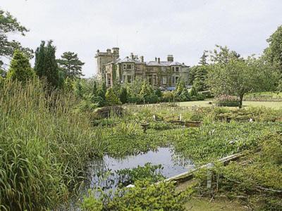 Un gran edificio en medio de un jardín con un estanque. en Lochnagar, en Largs