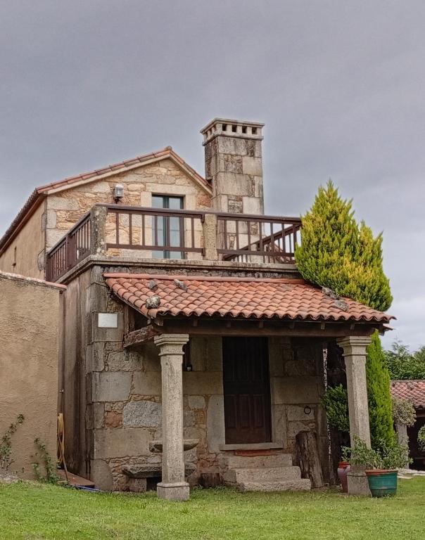 an old stone house with a balcony on top of it at A Casa da Rianxeira in A Pobra do Caramiñal