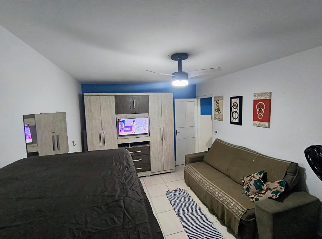 una camera da letto con un letto, un divano e una TV di Kitão Caiçara a Praia Grande