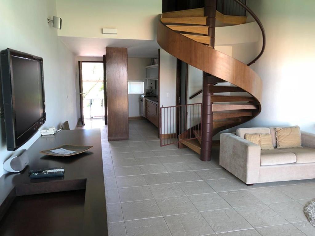 a living room with a spiral staircase and a couch at Flat 718, Villa hípica, Gravatá in Gravatá