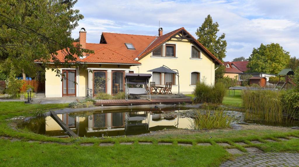 a house with a pond in front of it at Erdőparty Vendégház in Tápiószecső