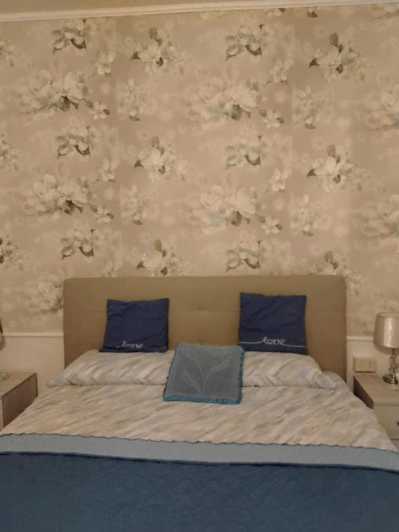 a bedroom with a bed with blue pillows and floral wallpaper at B&B Oasi di pace in Rocca deʼGiorgi