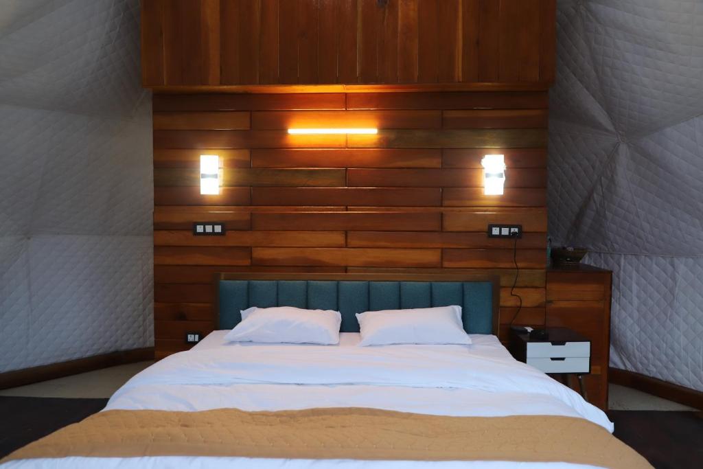 a bedroom with a large bed with a wooden wall at The Kamcha Geodesic dome & Homestay in Bomdila